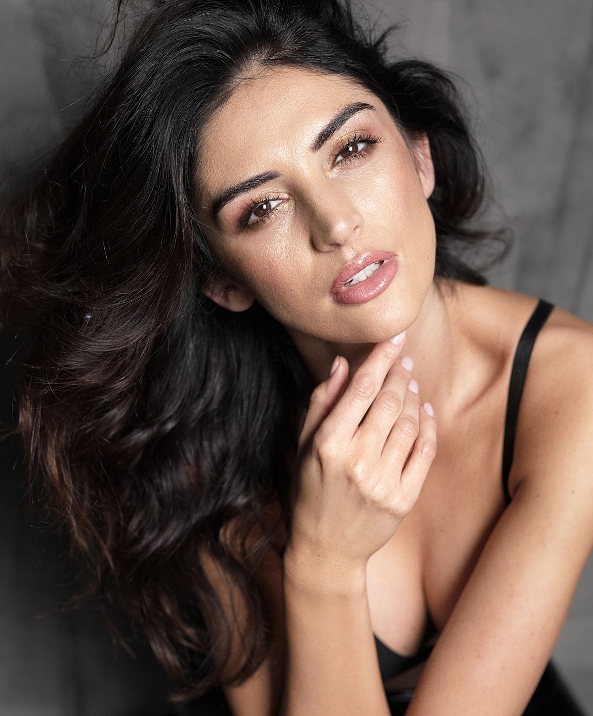 Woman with flowing hair resting her chin on hand.