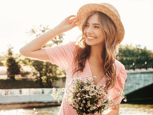 carefree woman posing on the street background in hat at sunset.